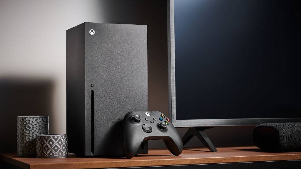 Xbox Series X console standing on a desk next to a TV