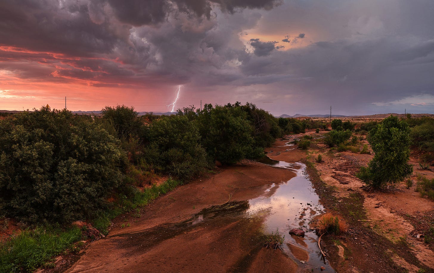 Lightning strikes during a monsoon storm with a nearly dry creek bed in the foreground on July 21, 2022 near Mayer, Arizona. 