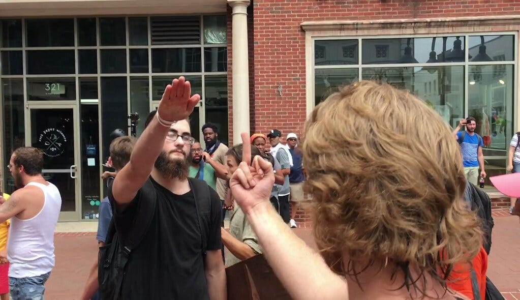 A counter-protester gives a white supremacist the middle finger. The white supremacists responds with a Nazi salute.