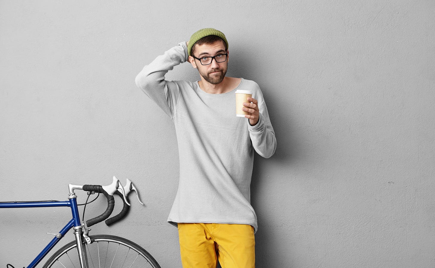 A lackadais man shrugs while he holds his coffee.