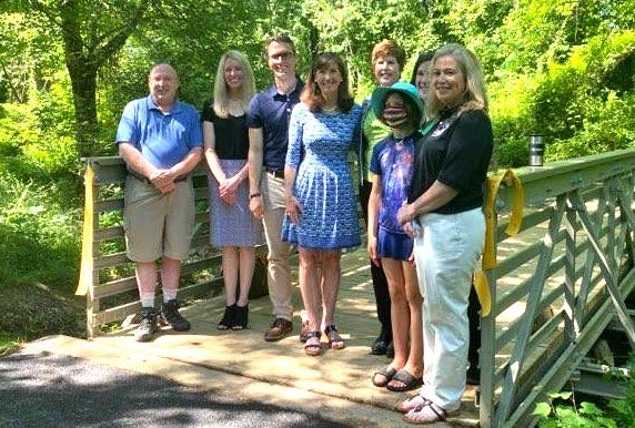 Supervisor Walkinshaw and seven Fairfax Park Authority officials standing in front of the pedestrian bridge and smiling at the camera