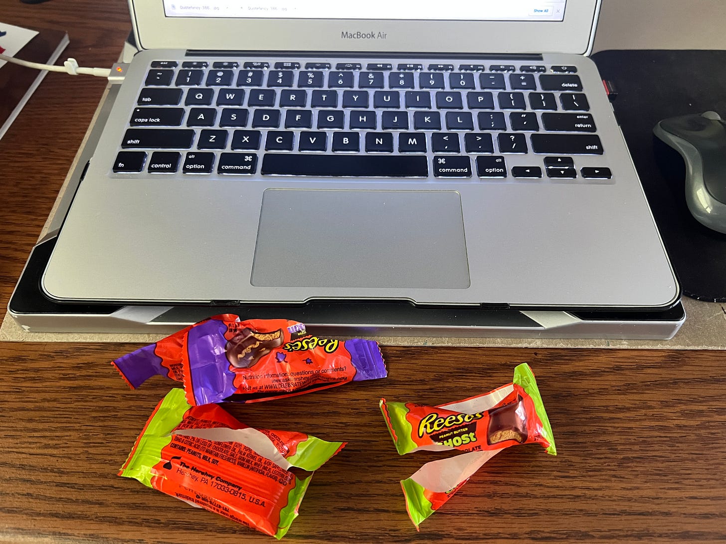 Laptop on desk with three empty wrappers of fun-size Reese's peanut butter Halloween figures.