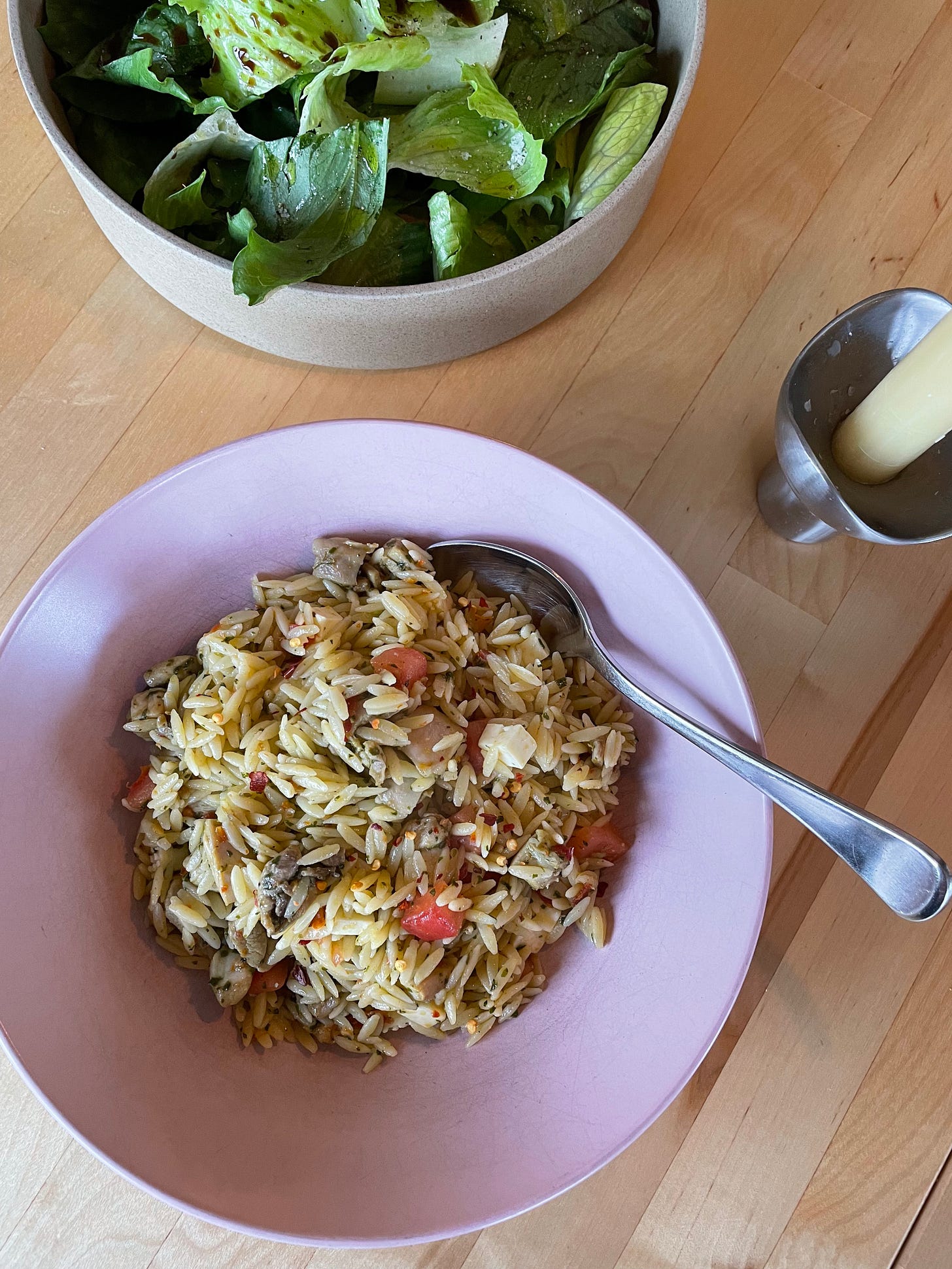 Bowl of chicken orzo salad with a green salad in the background. A summer meal.