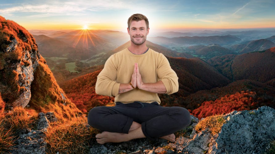 Actor Chris Hemsworth seated cross-legged on a hilltop