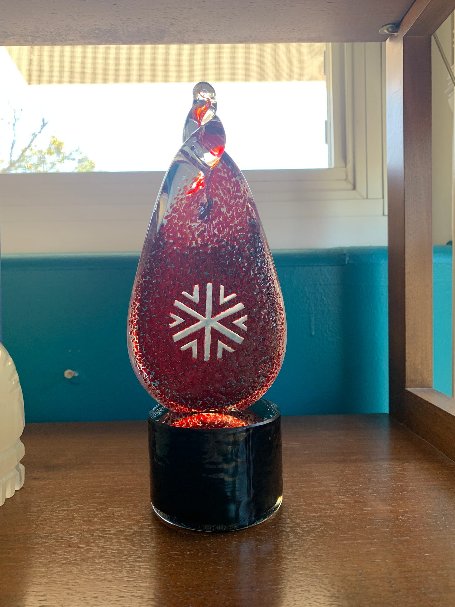 Caissie's Catalyst Festival Career Achievement Award, which she accepted after having an edible. It is red and clear glass, resembling a flame with a snowflake etched into it.