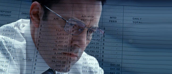 Cena do filme O contador. A imagem de um homem branco de óculos e camisa branca está sobreposta a um relatório financeiro em inglês.