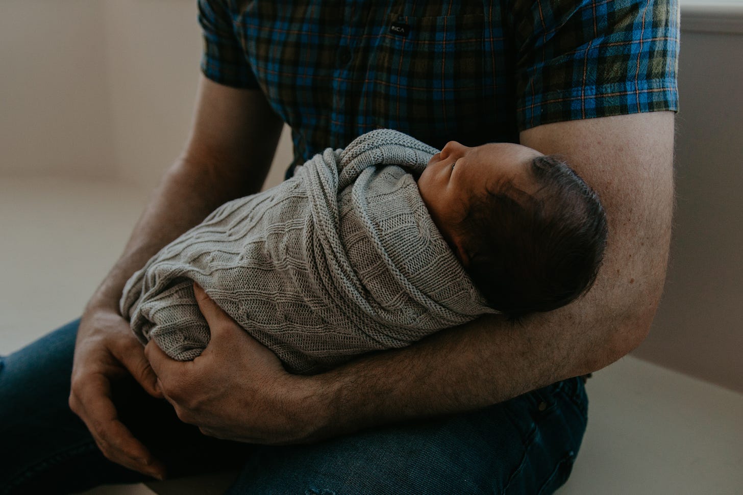 Photo of a dad cradling his baby in his arm by brooklyn on Unsplash