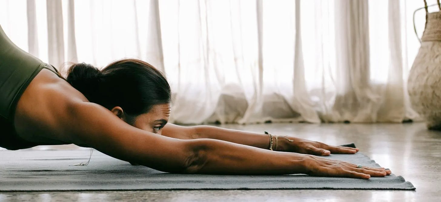 A closeup of a woman's torso, head, and arms on a yoga mat