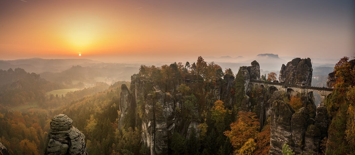 The Bastei Bridge in autumn/winter surrounded by trees and the landscape beyond at sunset