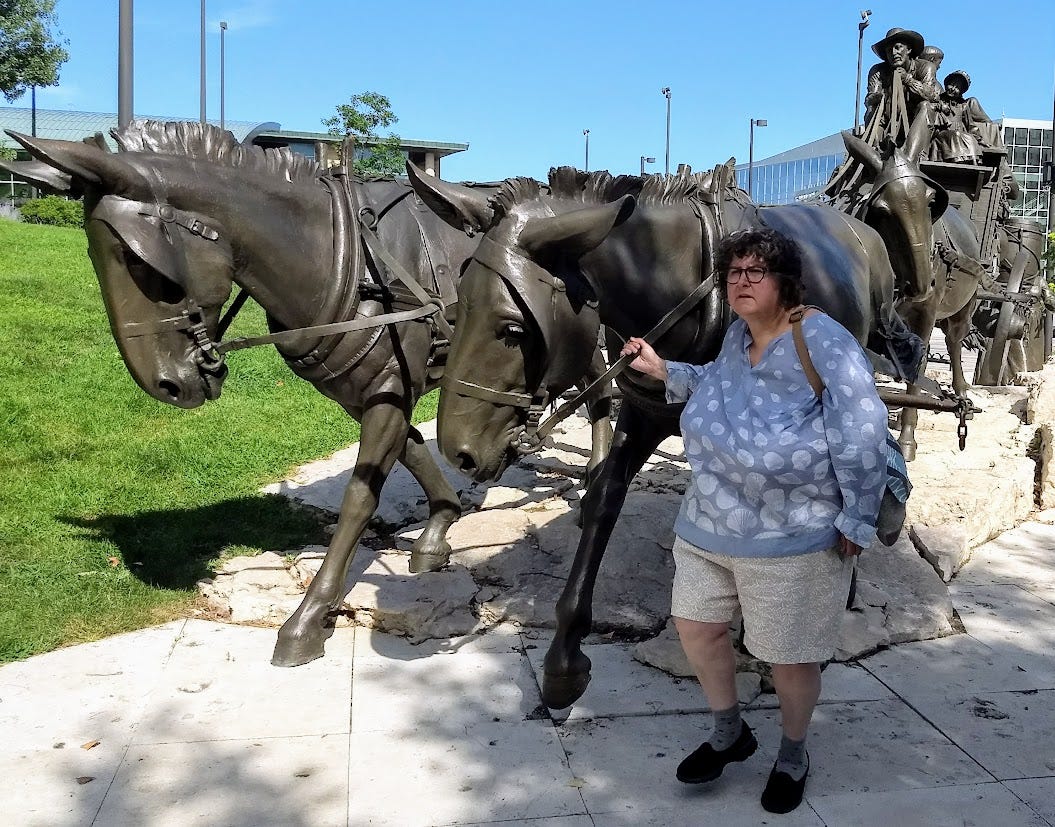 Woman with statues of stagecoach pulled by horses