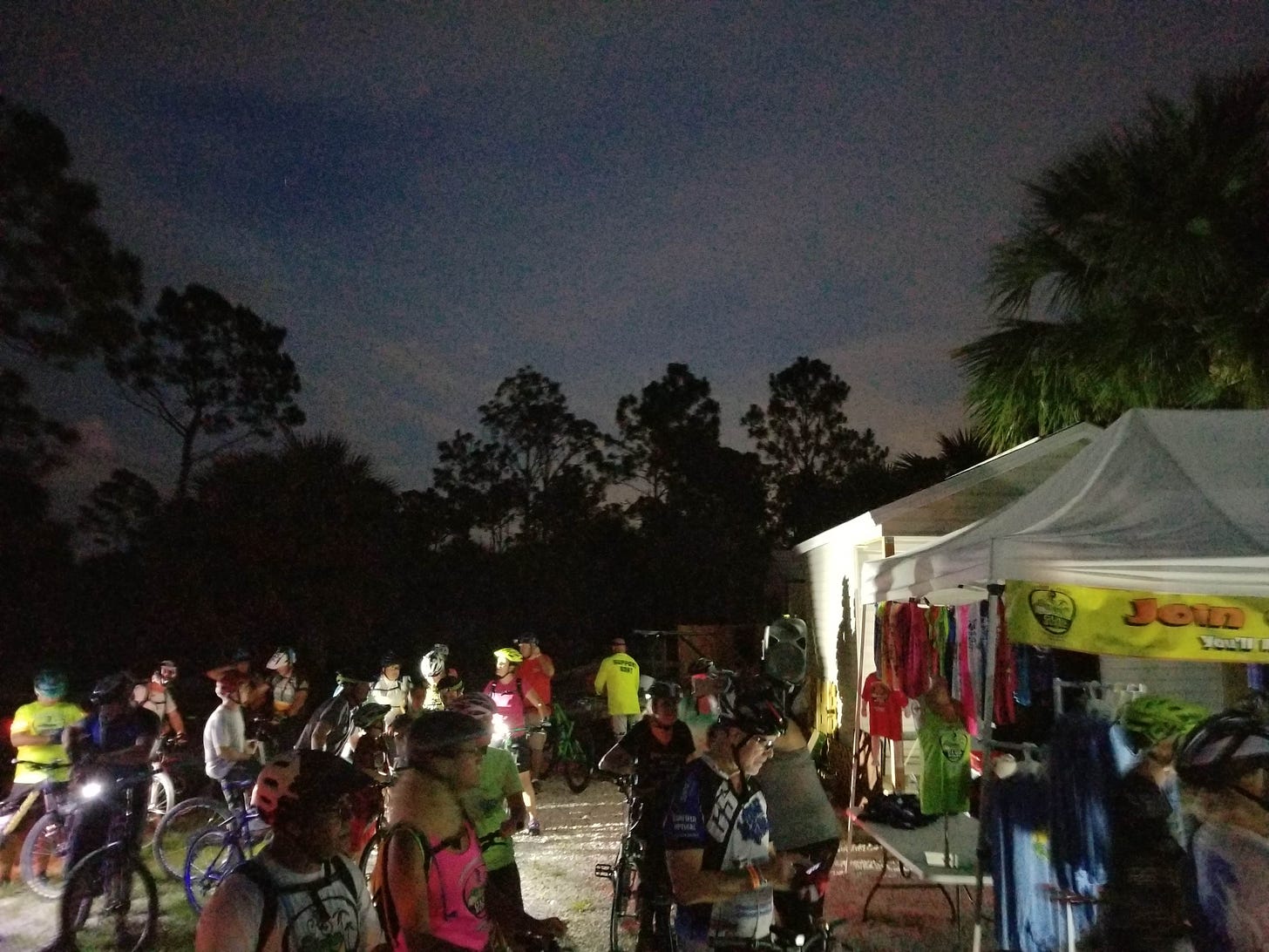 last light fades. a crowd of bikers prepare for the moonlit ride