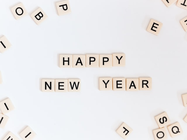 The words "Happy New Year" appear, with each letter on a tile resembling a Scrabble tile.