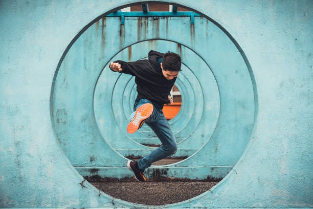 Young Asian active man in action of jumping and kicking, circle looping wall background. Extreme sport activity, parkour outdoor free running, or healthy lifestyle concept Young Asian active man in action of jumping and kicking, circle looping wall background. Extreme sport activity, parkour outdoor free running, or healthy lifestyle concept fearles stock pictures, royalty-free photos & images