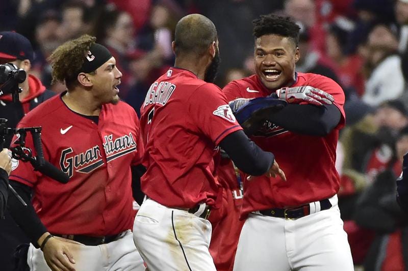 Cleveland Guardians' Oscar Gonzalez, right, and Josh Naylor, left, celebrate with Amed Rosario, center, after the Guardians defeated the New York Yankees 6-5 in Game 3 of a baseball AL Division Series, Saturday, Oct. 15, 2022, in Cleveland. (AP Photo/Phil Long)