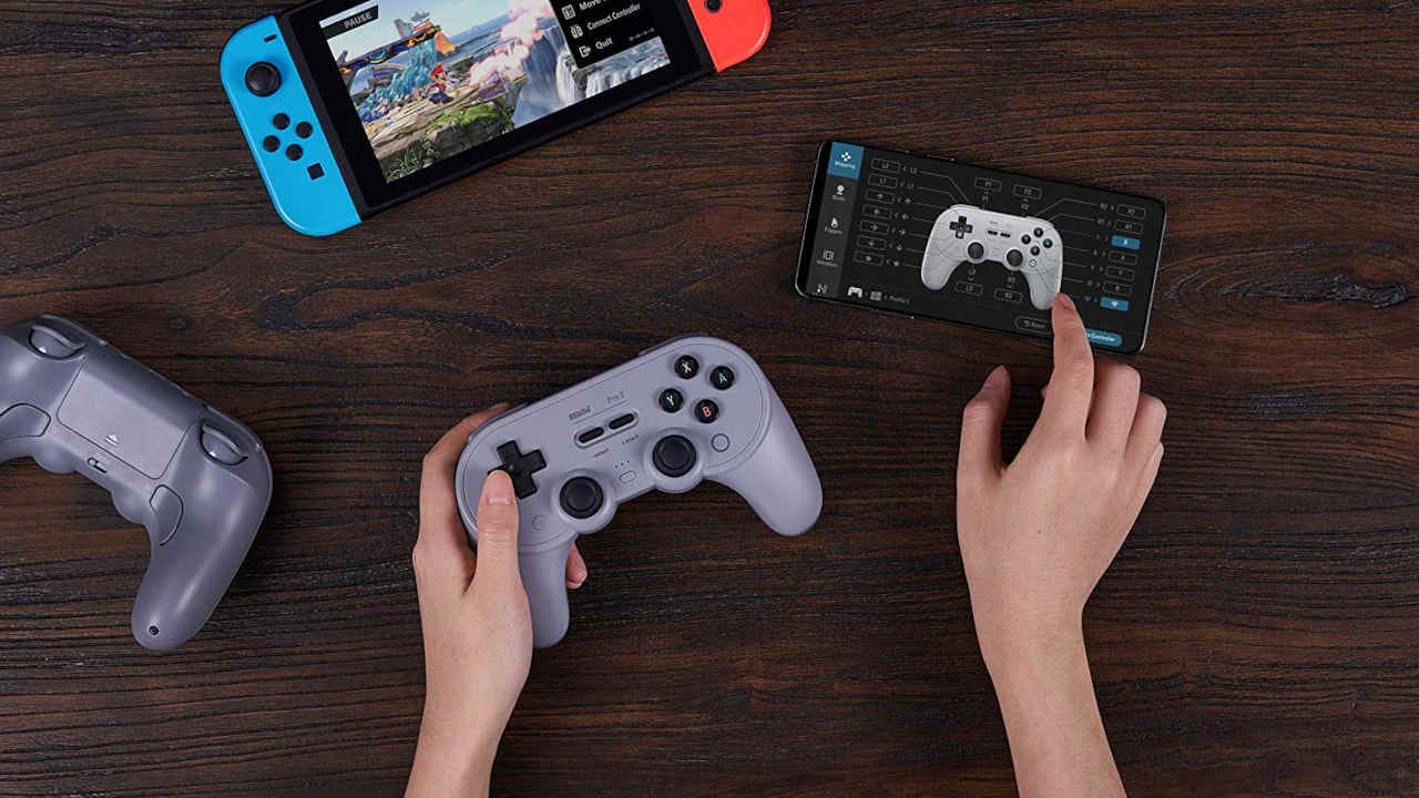 An 8BitDo Pro 2 controller next to a phone and Nintendo Switch