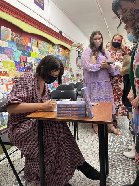 A photo of Kay signing books at the Brisbane launch of Social Queue