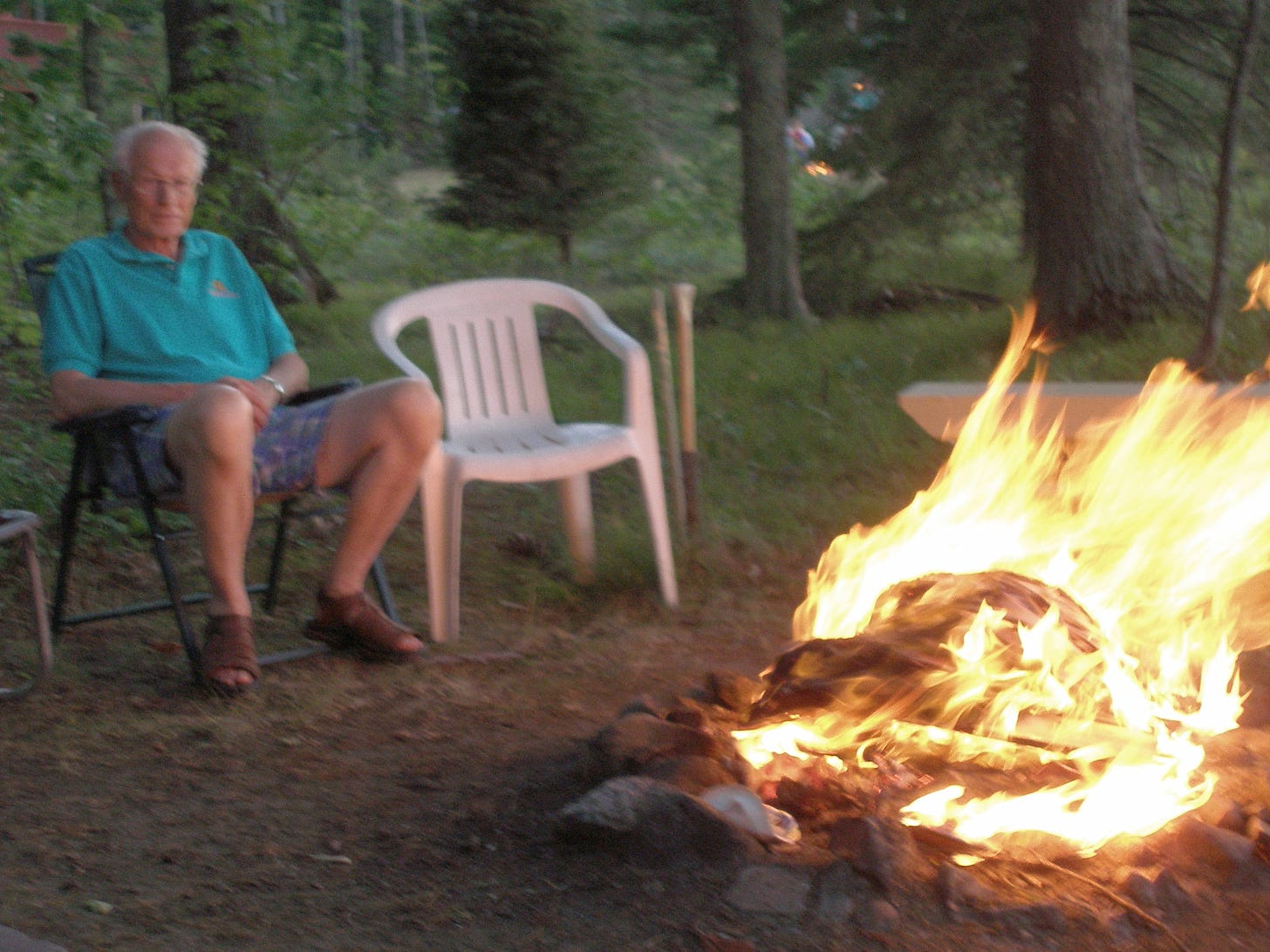 Grandpa Dick sitting by a campfire.