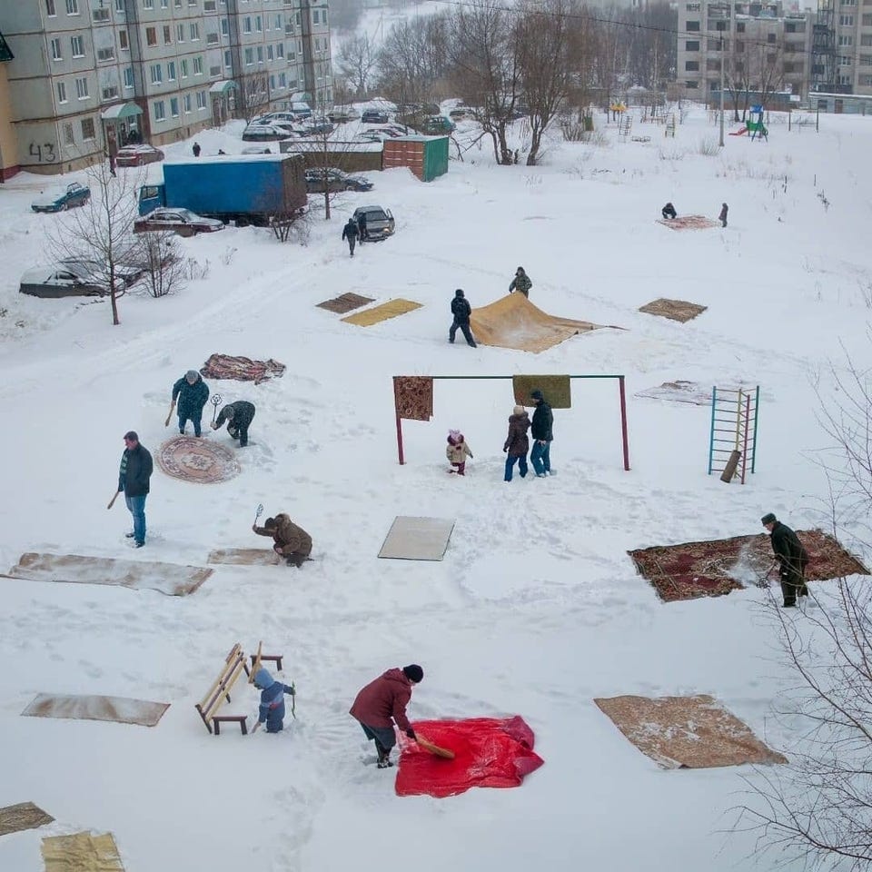 Russians cleaning carpets in the snow