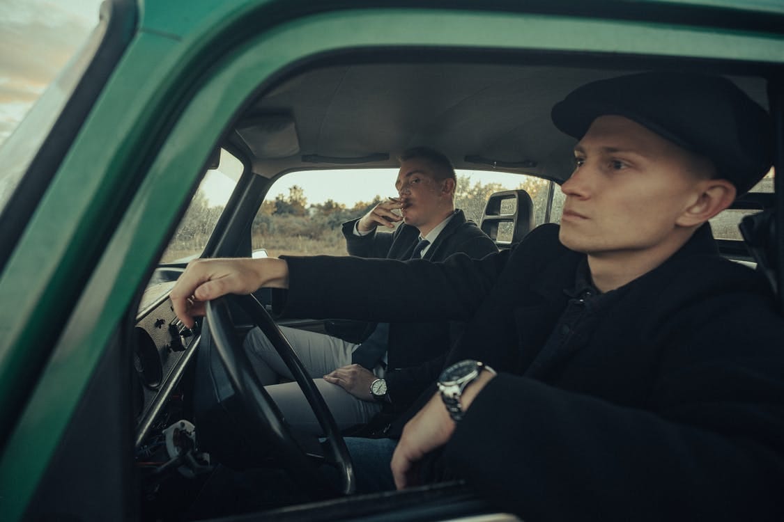 Two young man inside vintage car smoking cigarette 
