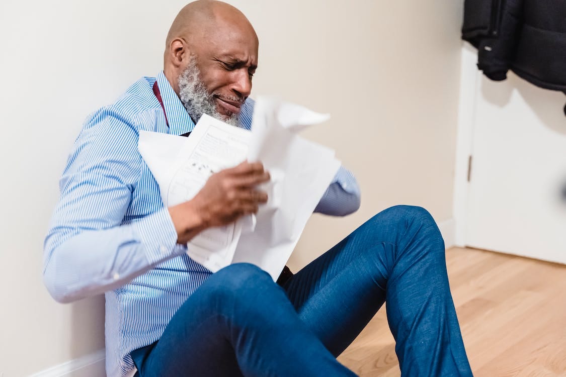 Free Man in White and Black Checkered Dress Shirt and Blue Denim Jeans Sitting on Brown Chair Stock Photo