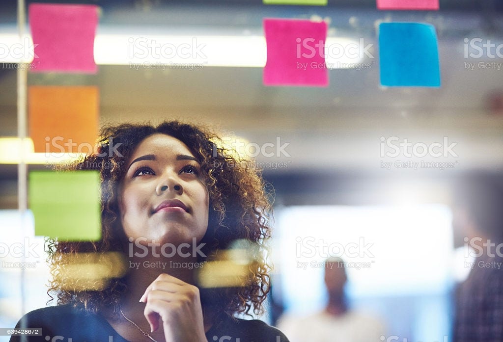 A person looking up at sticky notes placed on a glass wall with the iStock watermark