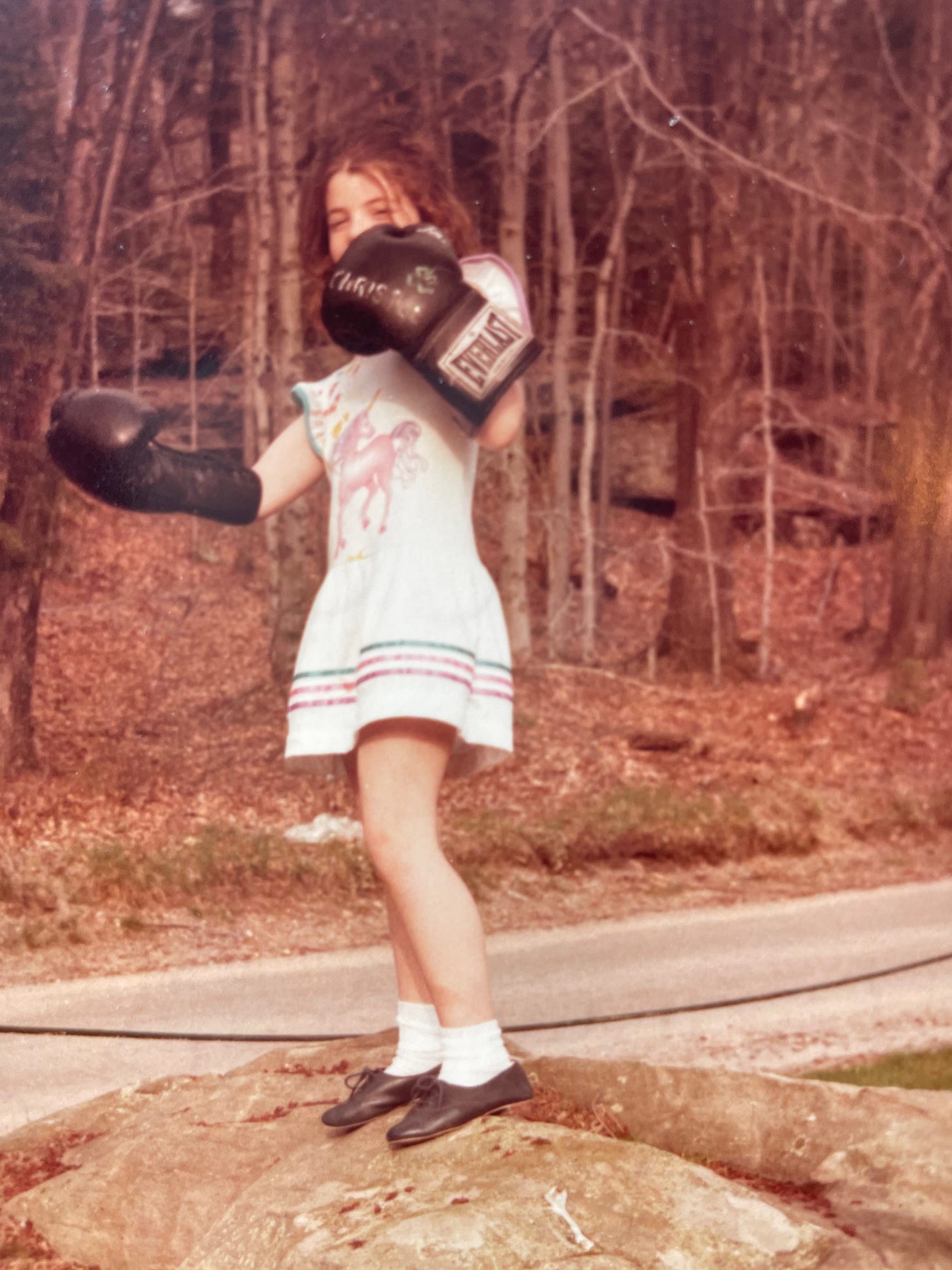 Little girl in a unicorn dress wearing Everlast boxing gloves