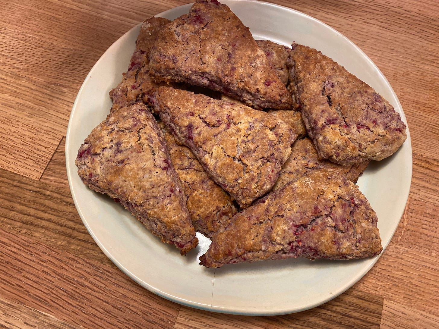 A plate of wedge-shaped raspberry scones on a wooden counter.