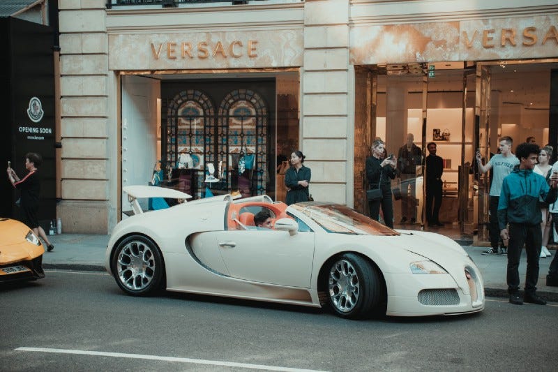 A young rich kid in a supercar in front of a Versace store