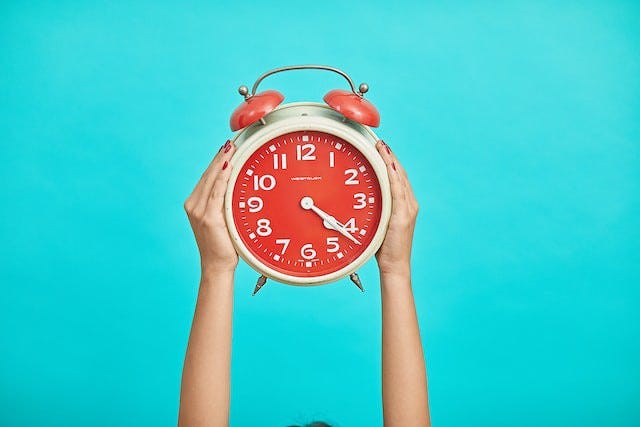 person holding a red clock aloft on a bluie background