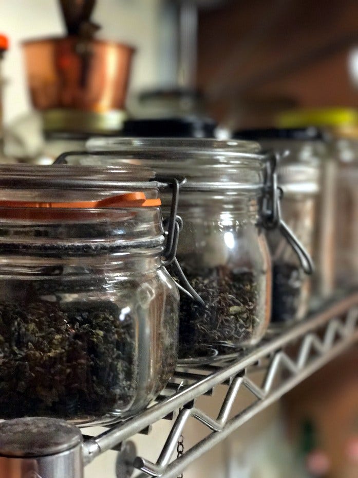 glass jars filled with looseleaf teas, sitting on a metal shelf