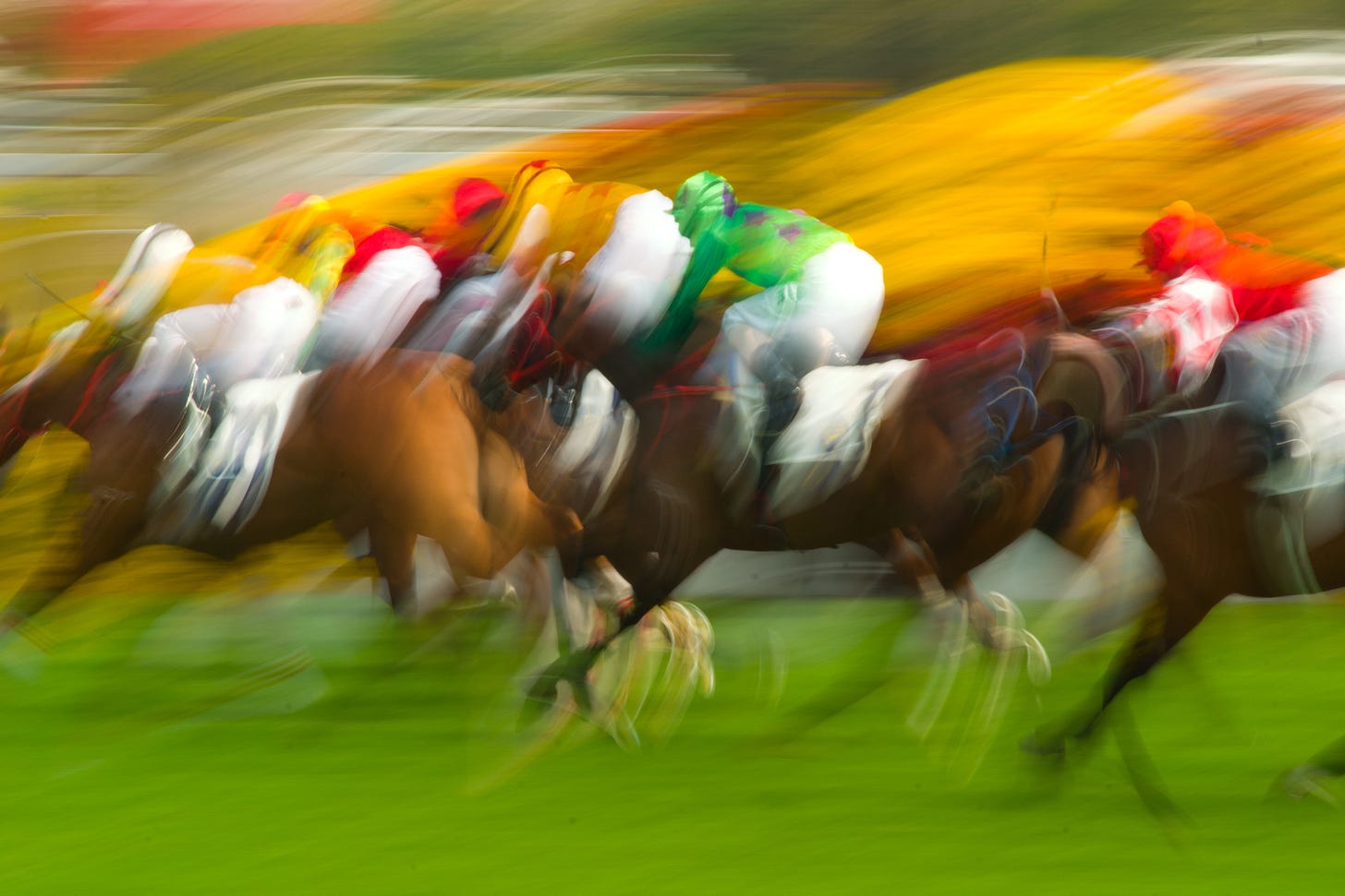 Blurry racehorses and jockeys in bright multicolored silks on a grass track. No mud, dry, probably pretty fast.I've played a horse or two in my life.