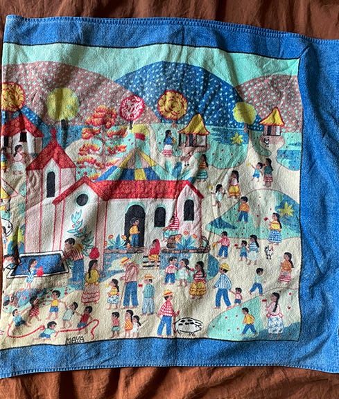 Towel depicting a church, children playing, mountains in the background