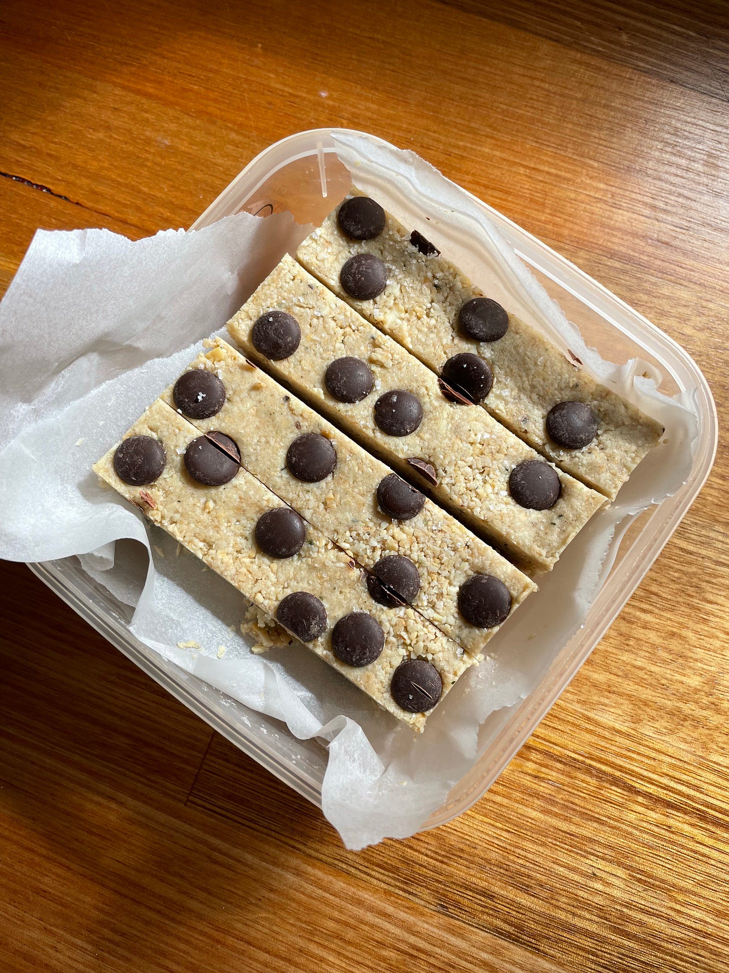 Container of homemade muesli bars with choc chips on top