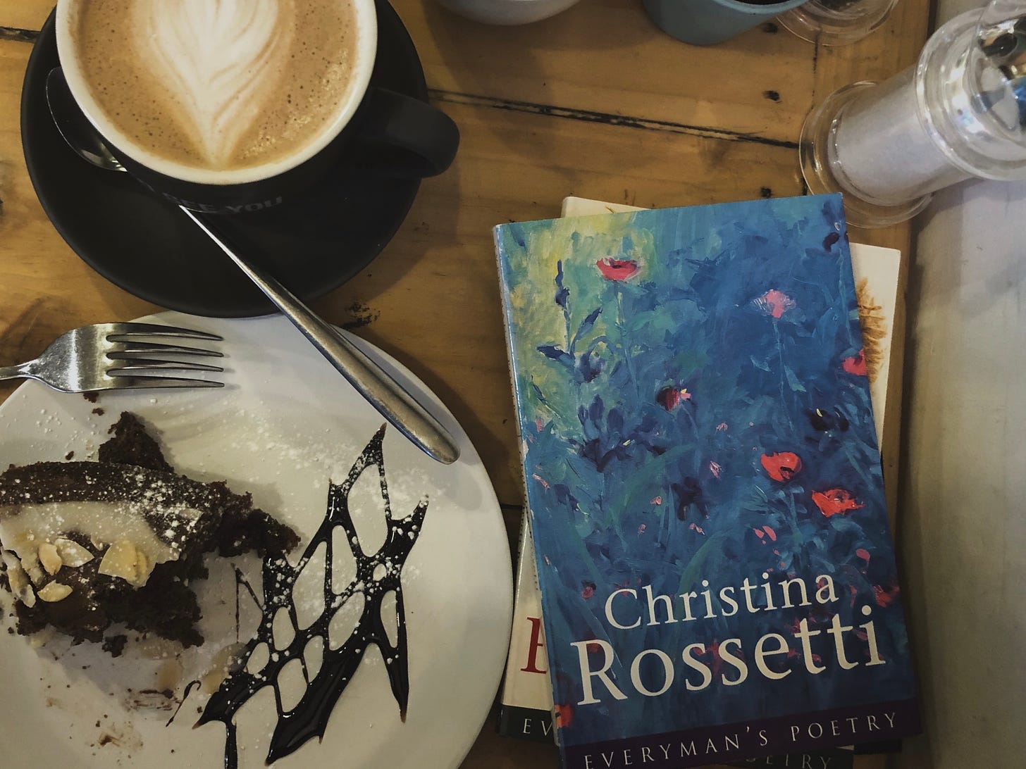 A cup of coffee with a collection of Christina Rossetti's poetry and cake