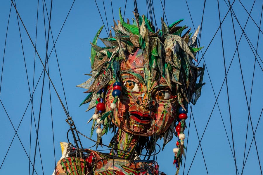 The head of a giant puppet is seen surrounded by cables.