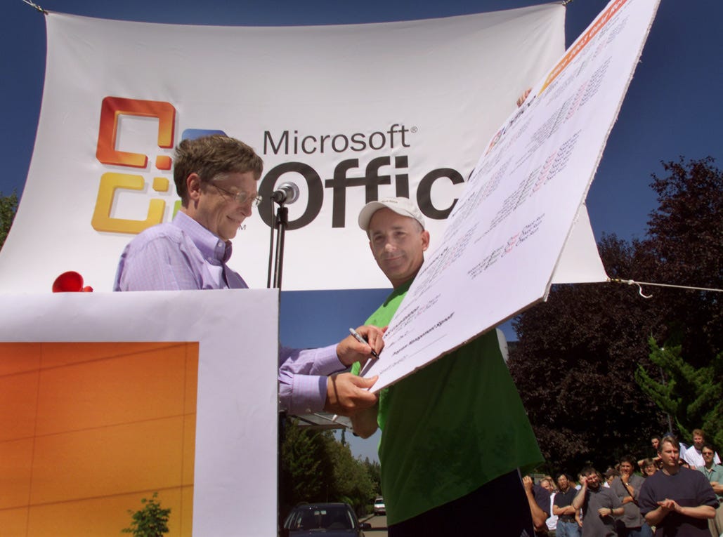 Photo of Bill Gates and Steven Sinofsky signing off on the release of Office 2003--bill is signing a giant facsimile of the release document.