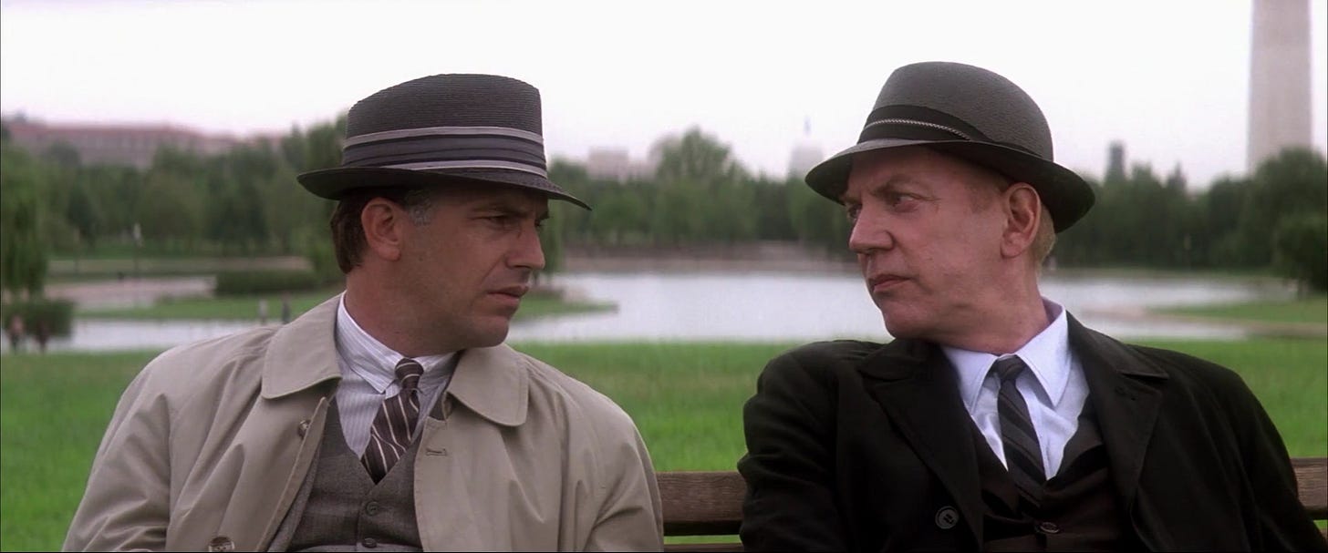 This image shows New Orleans District Attorney Jim Garrison (played by Kevin Costner, left) sitting on a park bench in Washington, D.C.'s National Mall next to a character known only as Mr. X (played by Donald Sutherland, right). Part of the Washington Monument is visible in the background. This image shows New Orleans District Attorney Jim Garrison (played by Kevin Costner, left) sitting on a park bench in Washington, D.C.'s National Mall next to a character known only as Mr. X (played by Donald Sutherland, right). Part of the Washington Monument is visible in the background.