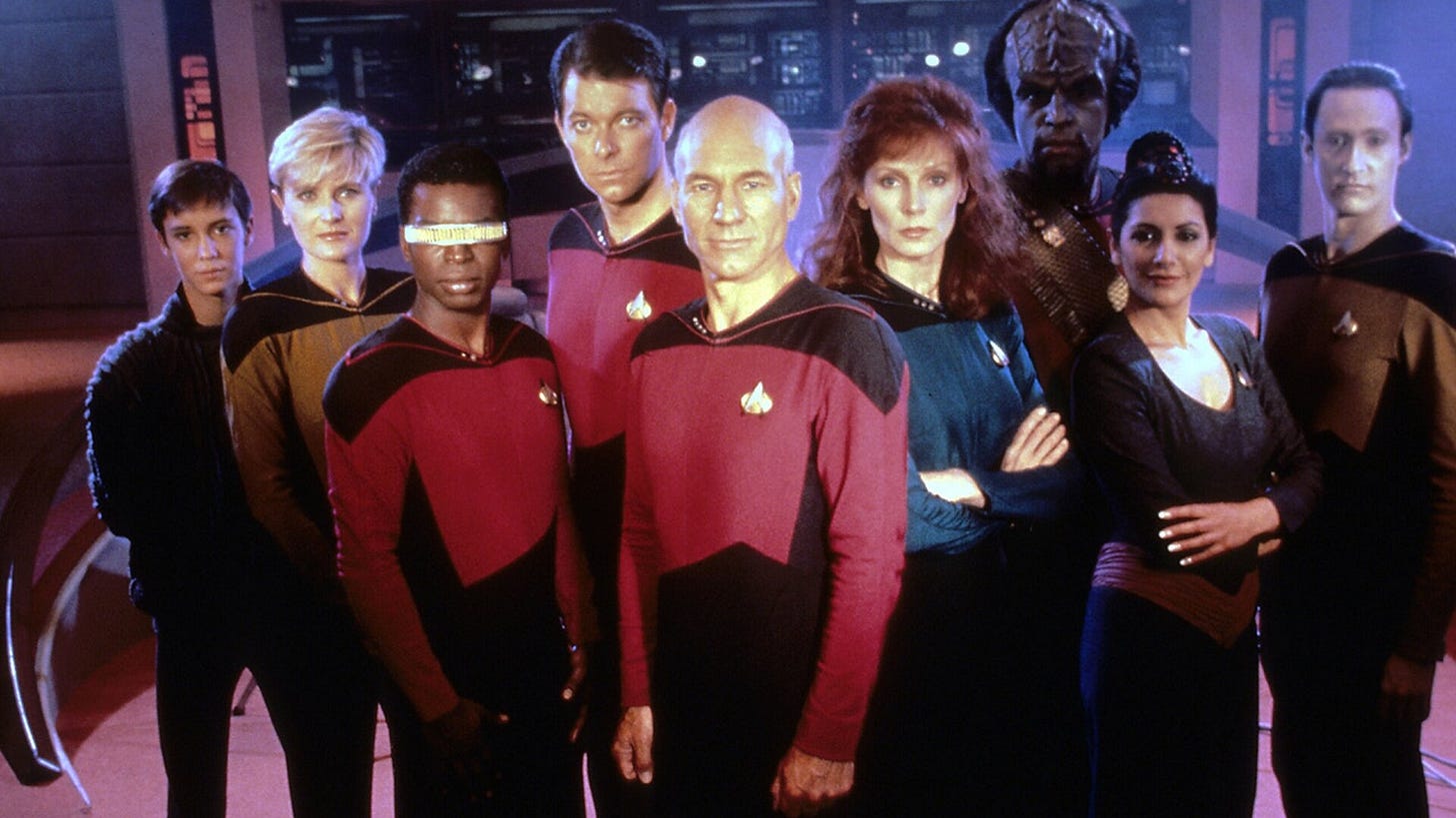 This image shows Star Trek: The Next Generation's Season 1 cast photo. From left to right are: Wesley Crusher (played by Wil Wheaton), Tasha Yar (played by Denise Crosby), Geordi La Forge (played by LeVar Burton), William T. Riker (played by Jonathan Frakes), Jean Luc-Picard (played by Sir Patrick Stewart), Dr. Beverly Crusher (played by Gates McFadden), Worf (played by Michael Dorn), Deanna Troi (played by Marina Sirtis), and Data (played by Brent Spiner). This image shows Star Trek: The Next Generation's Season 1 cast photo. From left to right are: Wesley Crusher (played by Wil Wheaton), Tasha Yar (played by Denise Crosby), Geordi La Forge (played by LeVar Burton), William T. Riker (played by Jonathan Frakes), Jean Luc-Picard (played by Sir Patrick Stewart), Dr. Beverly Crusher (played by Gates McFadden), Worf (played by Michael Dorn), Deanna Troi (played by Marina Sirtis), and Data (played by Brent Spiner).