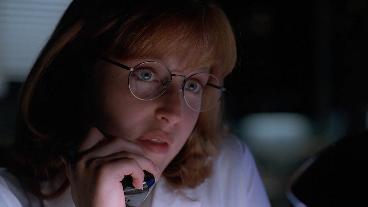 Scully with a fringe and round glasses, on the phone.