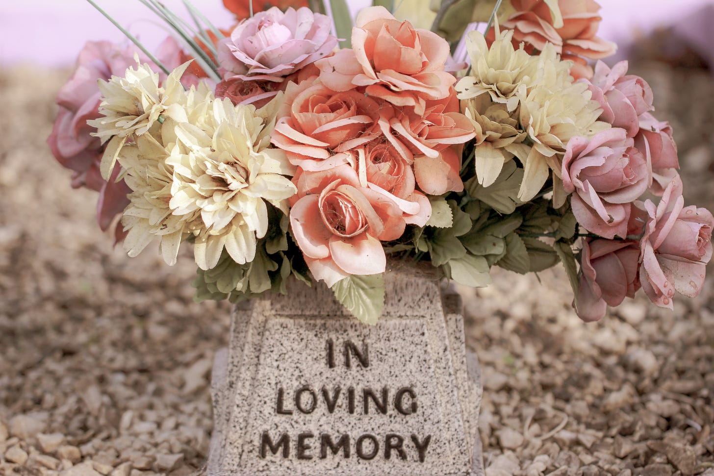 A bouquet of pastel-coloured flowers in a pot that reads 'In loving memory'.