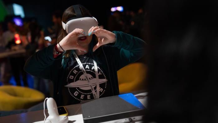 An exhibitor makes a heart gesture while wearing a Meta Oculus Quest 2 virtual reality headset at the NFT LA conference in Los Angeles, California, US