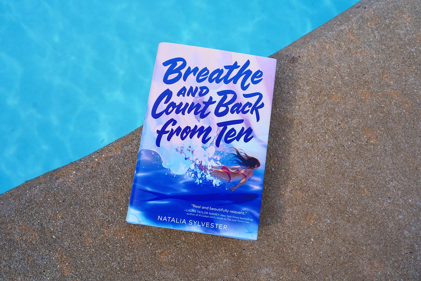 A photo of Breathe and Count Back from Ten sitting beside a pool