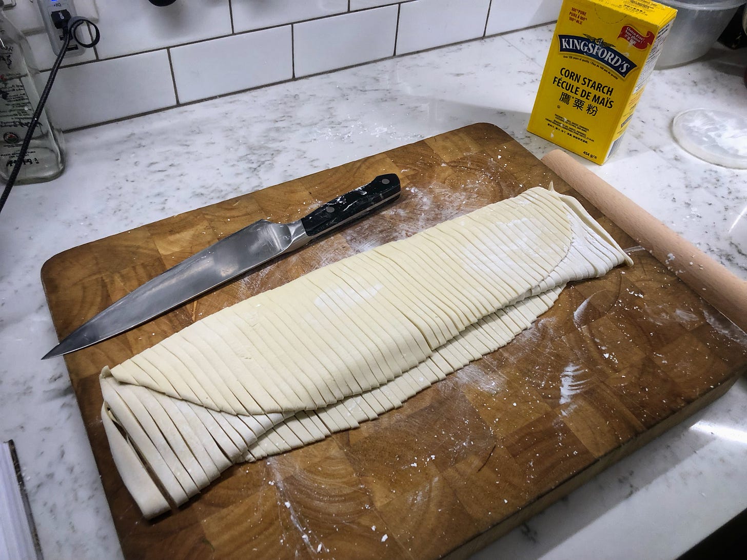 The folded dough sheet, cut into noodles and dusted heavily in corn starch