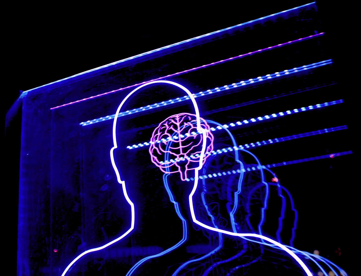 Outline of the upper part of a body with the outline of a brain in neon