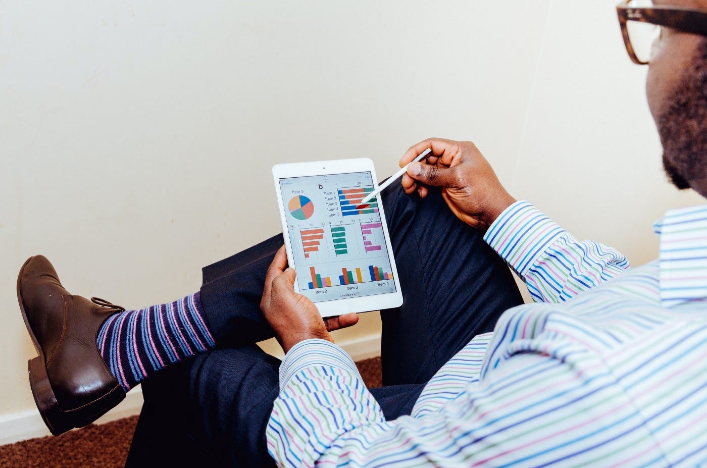 A businessman holding a tablet pen to a tablet and clicking on analytics like bar and line charts.