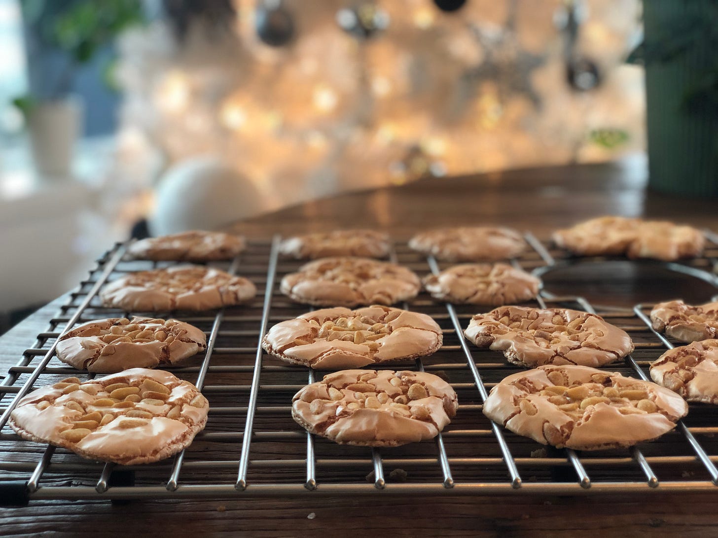 Pignoli cookies on a table in front of a white Christmas tree