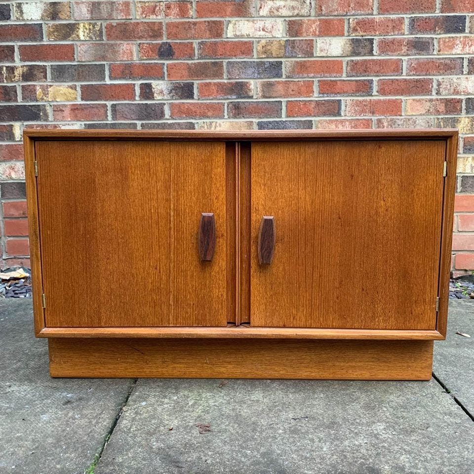 Gorgeous mid-century cabinet with a teak woodgrain and some storage space. Petite – about half a meter tall and wide, and 77 cm long.