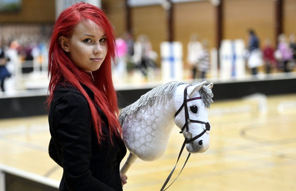 
              Sporting dyed red hair 20-year old Alisa Aarniomaki holds her hobby-horse, during the hobby-horsing Finnish championships in Vantaa, Finland, Saturday, April 29, 2017.  Thousands of young people in Finland have taken up hobby-horsing, with its strong therapeutic element and a social media subculture, it is physically demanding with gymnastic moves for the dressage and show jumping disciplines. (Heikki Saukkomaa/ Lehtikuva via AP)
            