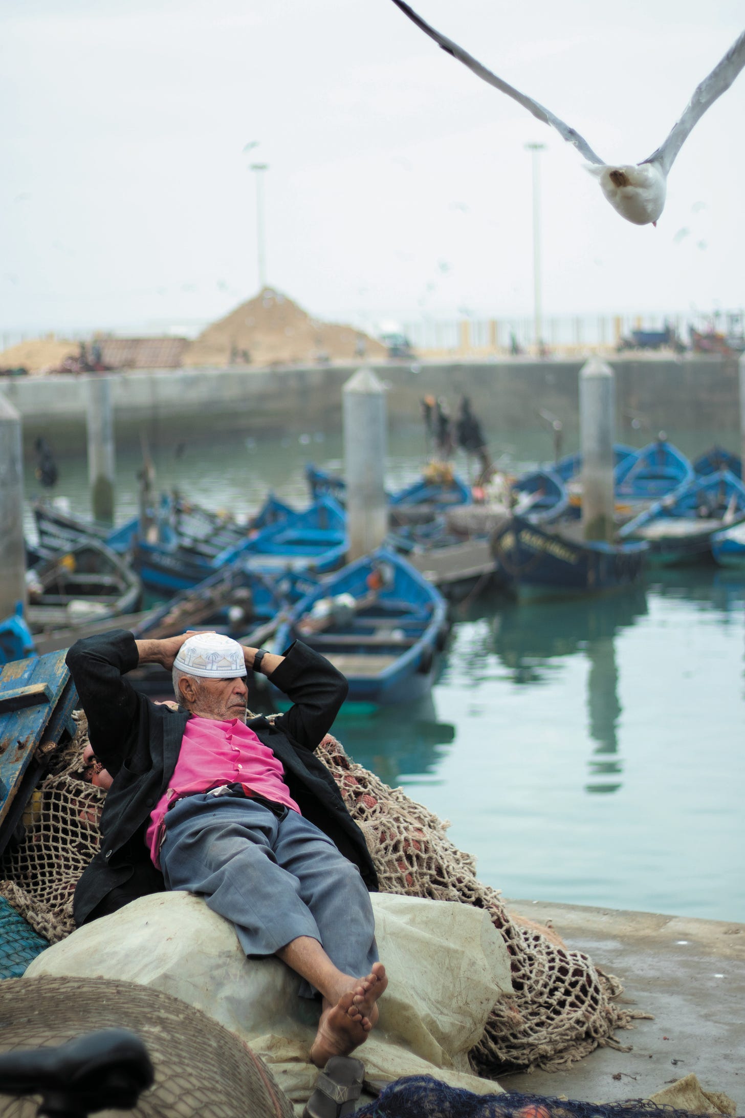 man relaxing on a fishing net in a harbour