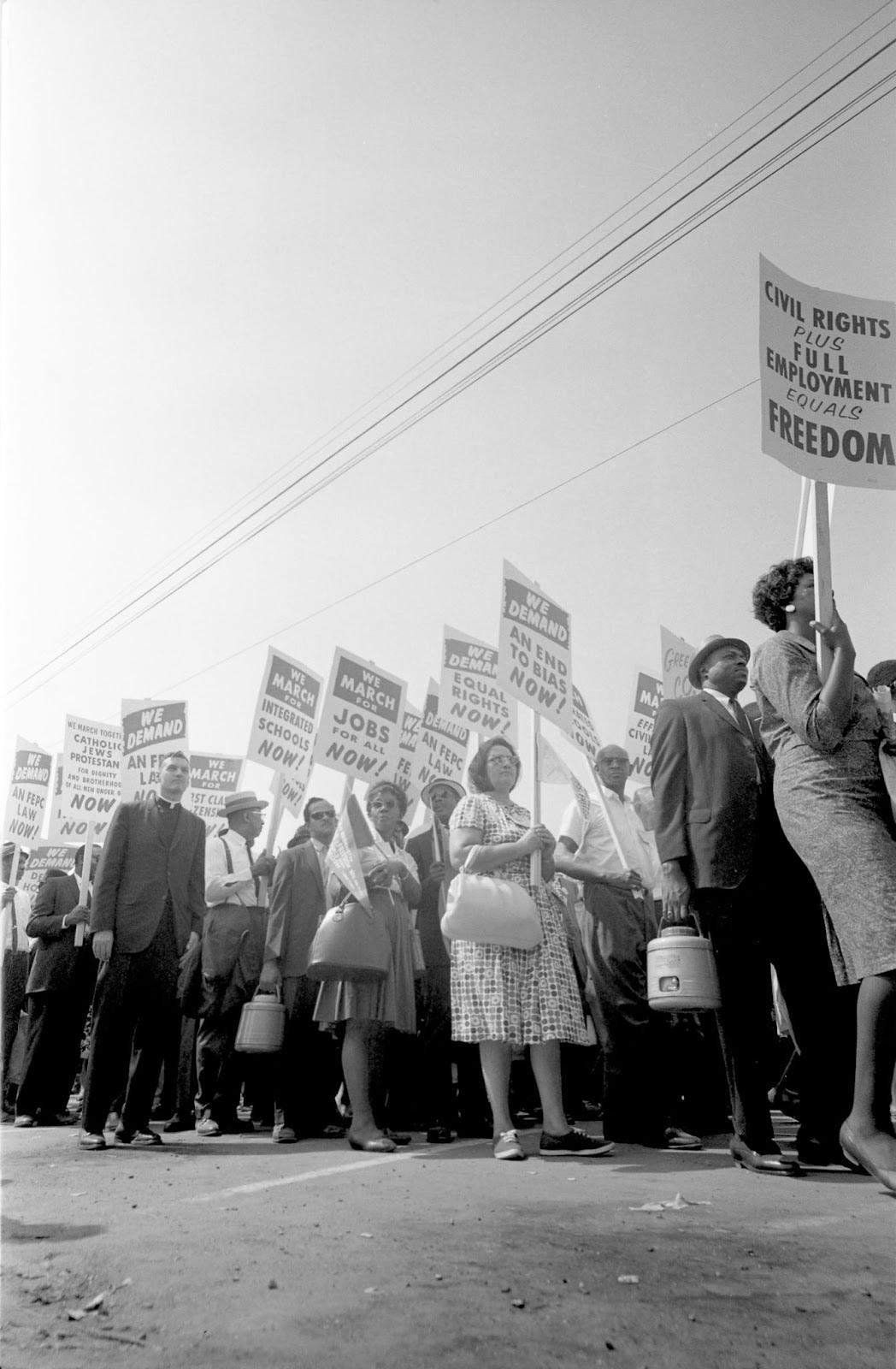a line of people marching with picket signs saying "civil rights plus full employment equals freedom"